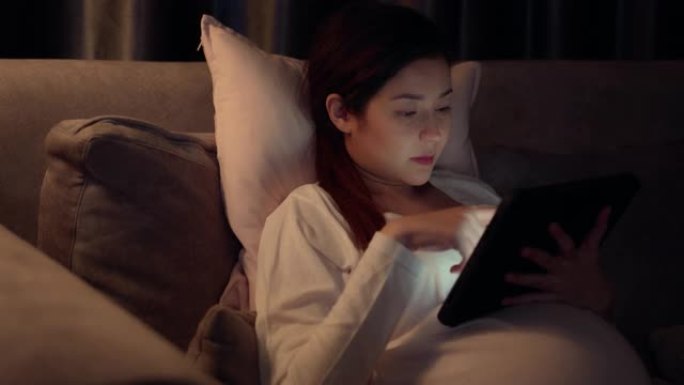 怀孕妇女使用数字平板电脑在晚上在家工作。