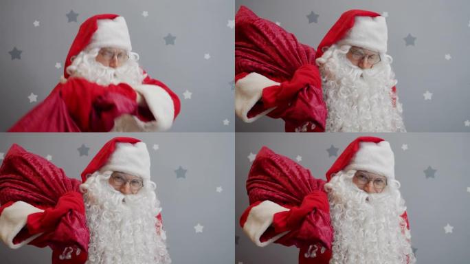 圣诞老人举起一袋礼物，看着相机，在繁星点点的背景上眨眼