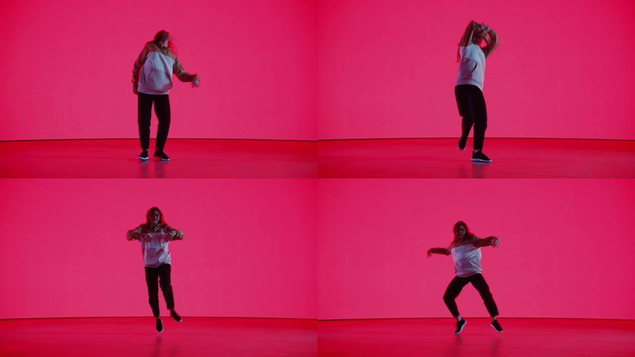 在工作室环境中的虚拟制作过程中，时尚的专业女舞者在红色背景的大Led墙屏幕前表演嘻哈舞蹈套路。