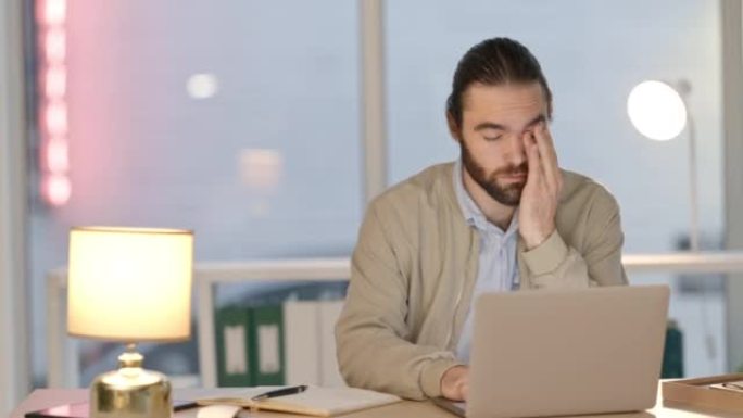 疲倦的商人深夜在笔记本电脑上工作。现代企业工人在下班后写数字报告或项目，以满足截止日期。昏昏欲睡的工
