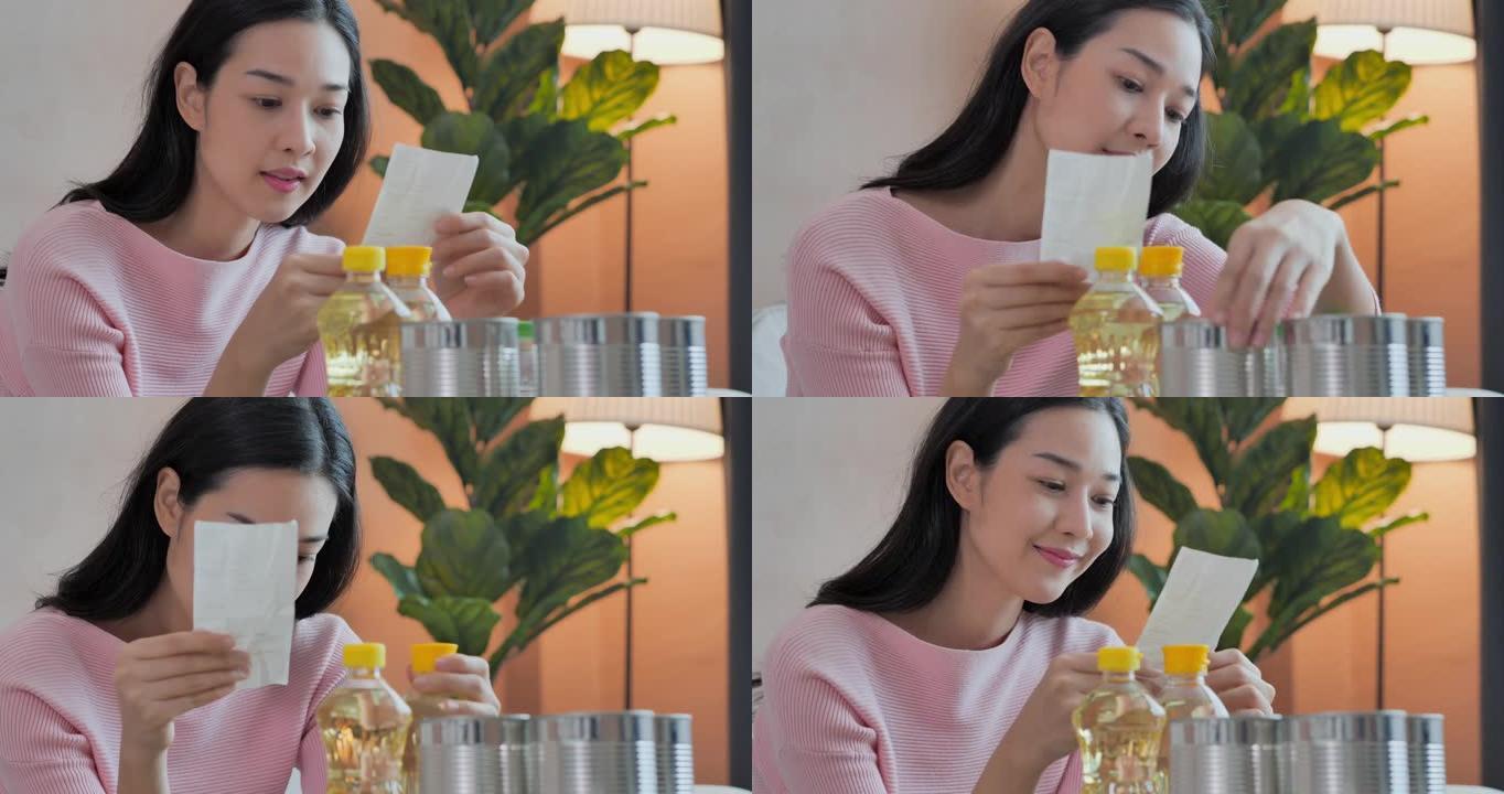 美丽的亚洲年轻女子年龄30岁，穿着粉红色衬衫坐在沙发上，收到网上购物订单，同时在家里查看消费品账单。