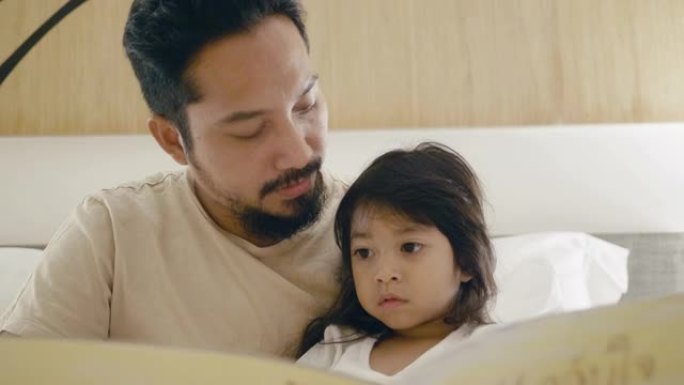 父亲和小女孩在床上读故事书。