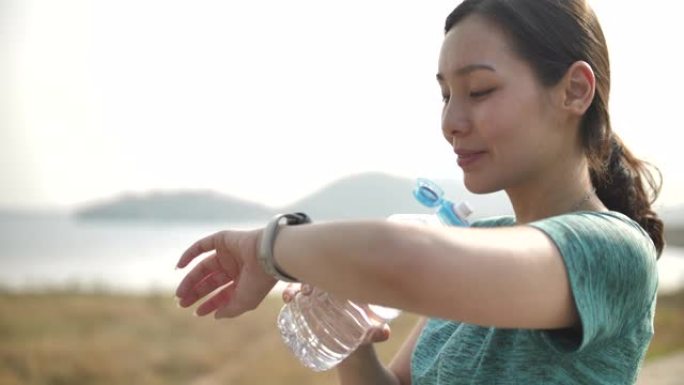 运动女人看着智能手表和饮用水