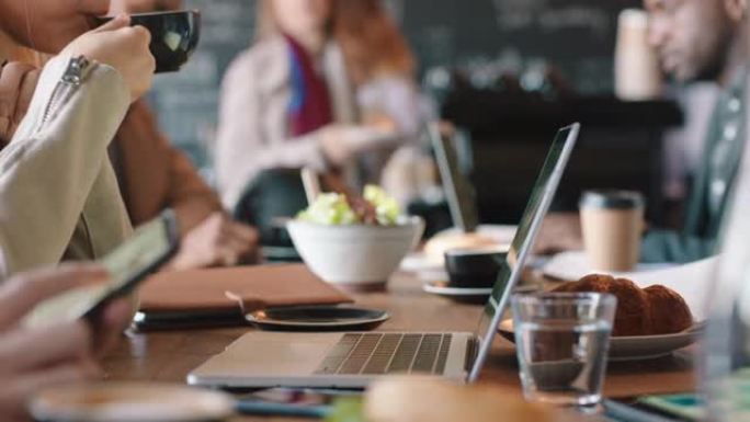 商务女性在咖啡馆用笔记本电脑在网上打字电子邮件在繁忙的餐厅享受喝咖啡放松午餐