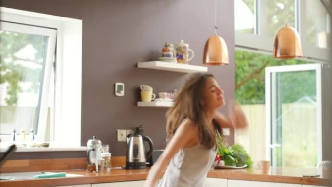 4k视频片段，一名年轻女子在厨房里跳舞