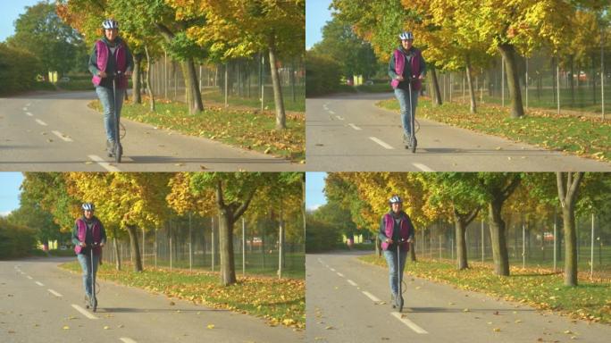 在美丽的秋日享受电动滑板车骑行的高级女士