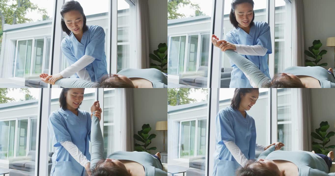 微笑的亚洲女性理疗师在手术中治疗躺在床上的女性患者的手臂