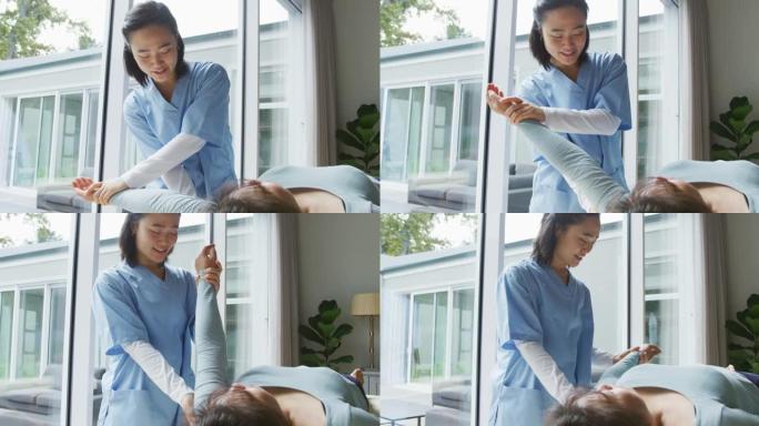 微笑的亚洲女性理疗师在手术中治疗躺在床上的女性患者的手臂
