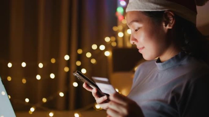 亚洲女性在圣诞节使用智能手机和卡片在线购买