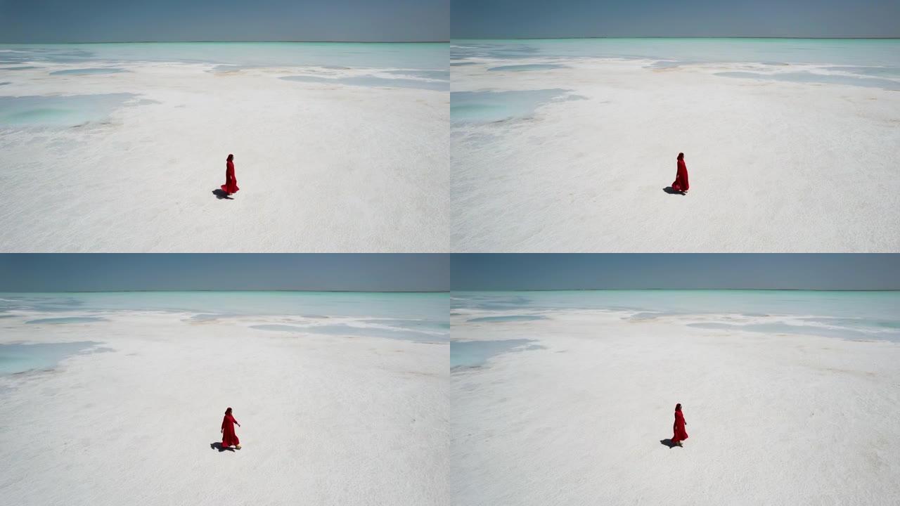穿着红色连衣裙走在盐湖上的女人的鸟瞰图