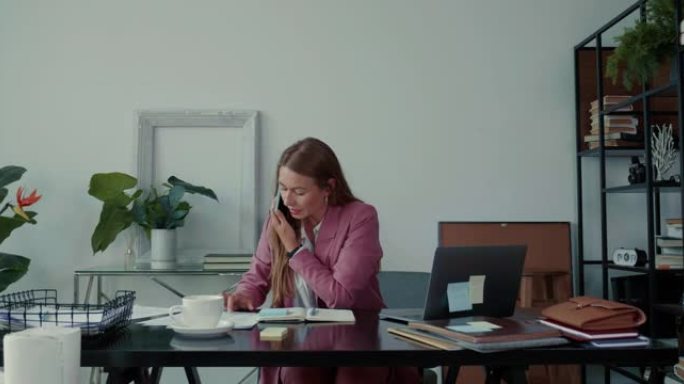 工作压力。美丽严肃的女商人通过电话交谈，在办公桌上忙于咨询笔记本电脑。