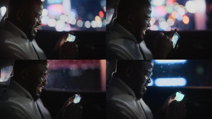 时髦的戴眼镜的黑人在晚上坐出租车的后座上下班。英俊的男性在智能手机上玩策略视频游戏，在城市街道上开着