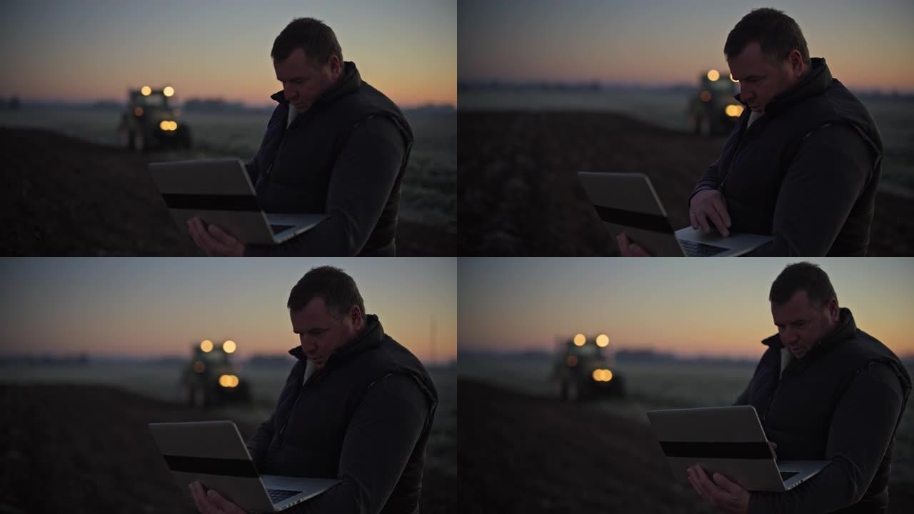 农民带着笔记本电脑在日出时在农田里工作