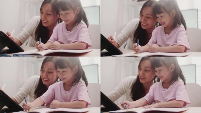 母亲在帮助女儿在家做功课时使用笔记本电脑