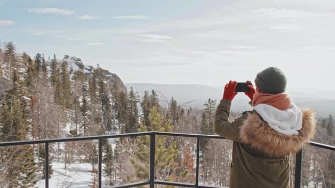 拍摄风景的女孩站在山顶拍照大自然冬景冬天