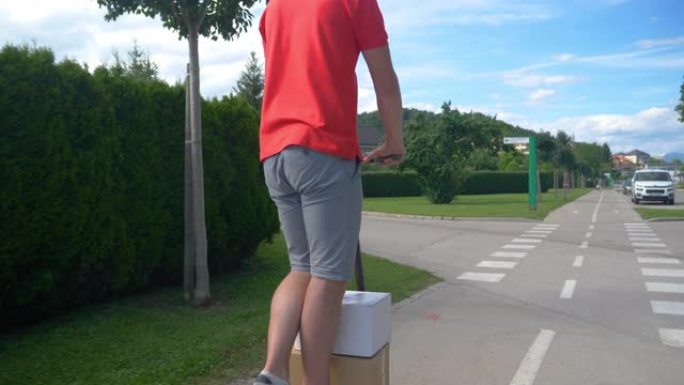 特写: 送货员带着两个包裹在人行道上骑着电动踏板车