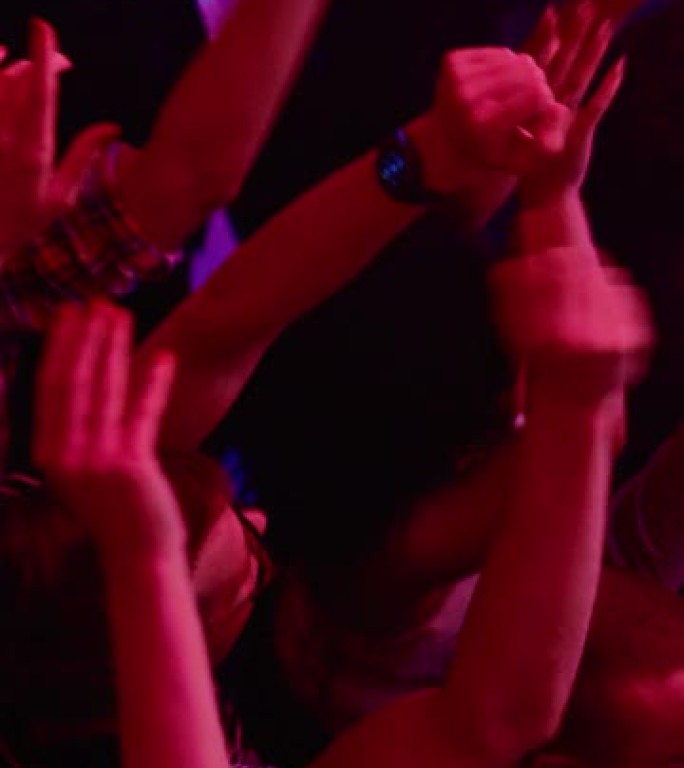 在夜总会的一场音乐会上，音乐节观众聚会的垂直镜头举起手来。来自上方的镜头，歌迷为摇滚或独立乐队欢呼。