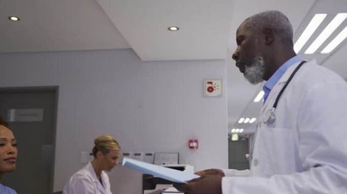 医院接待处的多元化男性医生并与女性工作人员交谈