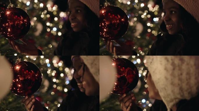 年轻女子的特写镜头，十几岁的妹妹在圣诞树上触摸小玩意