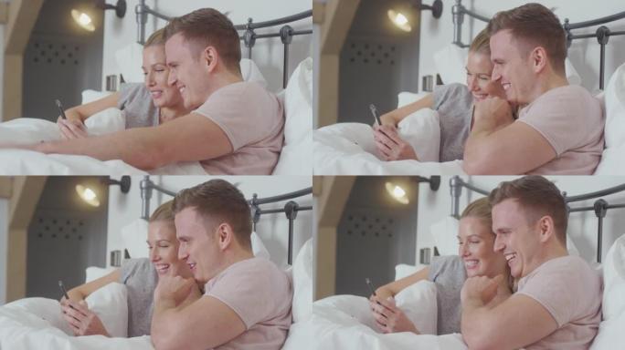 情侣在床上穿着睡衣一起看手机