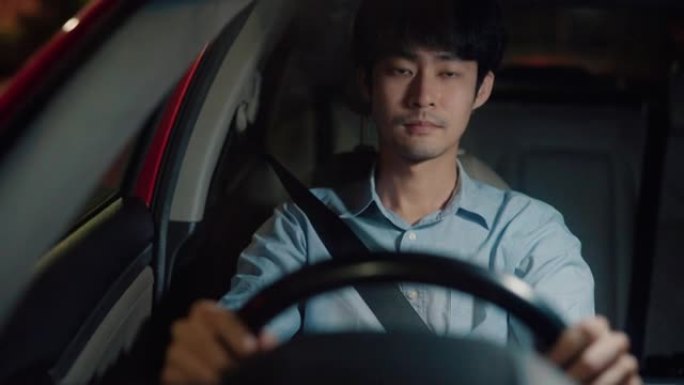亚洲男子在夜间驾驶时调整后视镜。