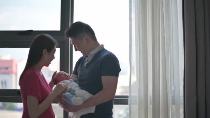 亚洲华裔父母带着爱在卧室里抱着他们刚出生的男婴