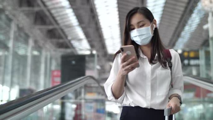 亚洲女子戴口罩在机场使用手机