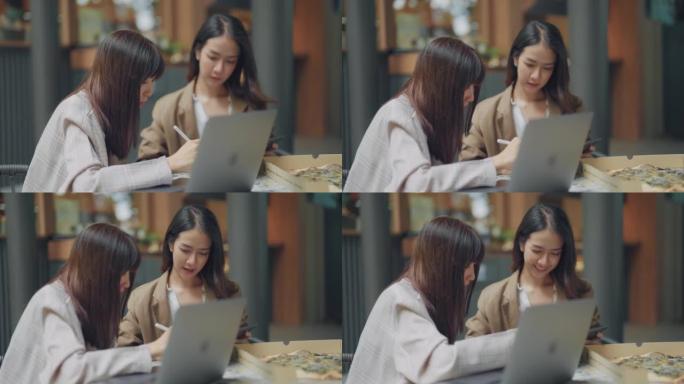 两个亚洲女性商业伙伴在咖啡馆聊天。