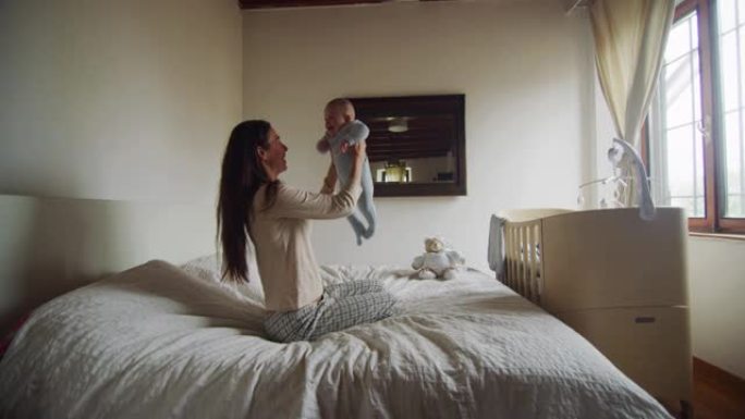 母亲在床上与新生婴儿玩耍的真实镜头