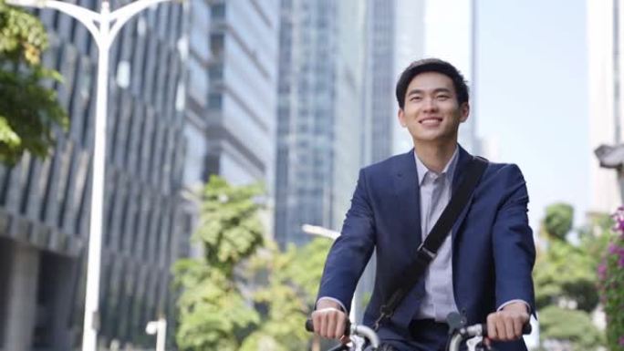 年轻的亚洲商人在现代城市骑自行车上下班