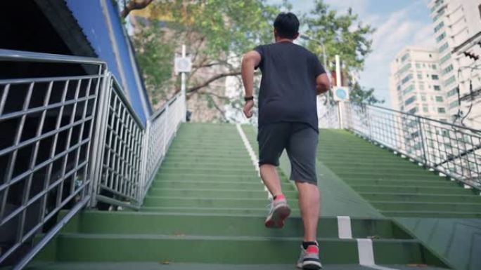 迷人的亚洲成年男子在城市跑步或慢跑。进行运动训练的男性通过在早上进行街头城市跑步来挑战自己。