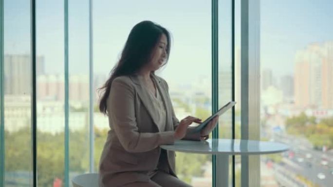 亚洲女企业家通过窗口使用数字桌子