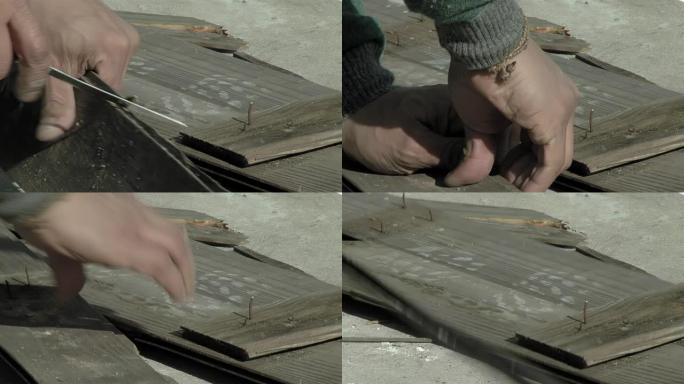 男人在户外做风筝时用刀切割一块旧木板。低角度视图。特写。