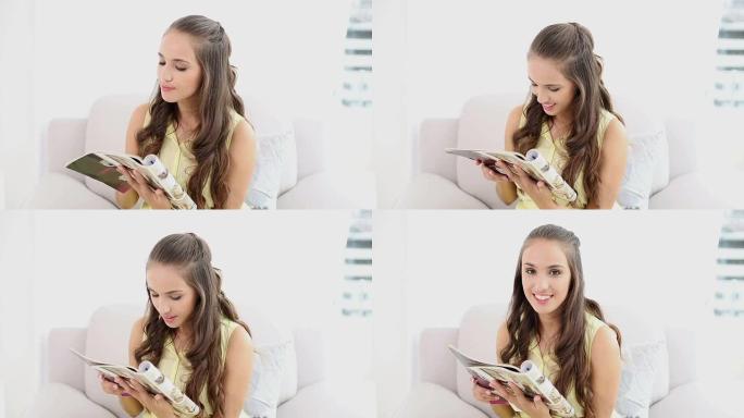 年轻女子微笑着在沙发上阅读杂志