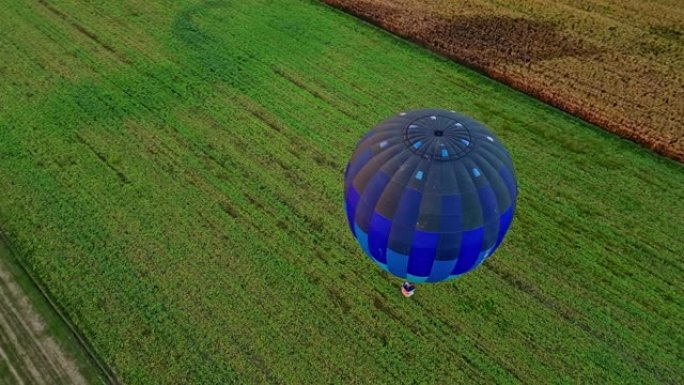 无人机的观点蓝色热气球飞越乡村田野