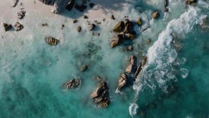 在美丽的热带岛屿海滩上直视海鸟飞行和绿松石波浪在岩石上破碎的鸟瞰图