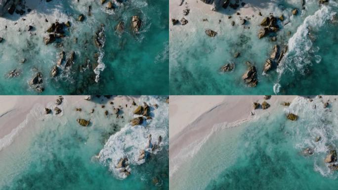 在美丽的热带岛屿海滩上直视海鸟飞行和绿松石波浪在岩石上破碎的鸟瞰图