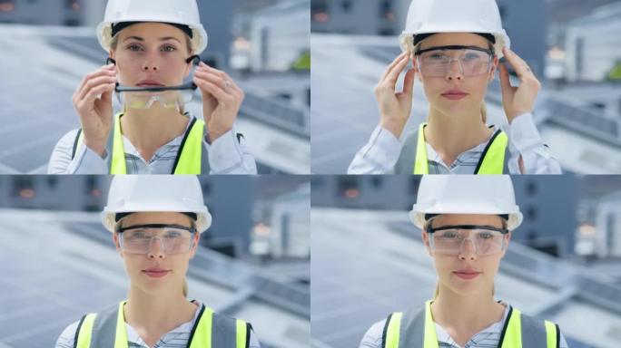 一名年轻的白人妇女在安装太阳能电池板时戴着护目镜和安全帽。一位自信的女员工站在建筑工地的建筑物上的肖