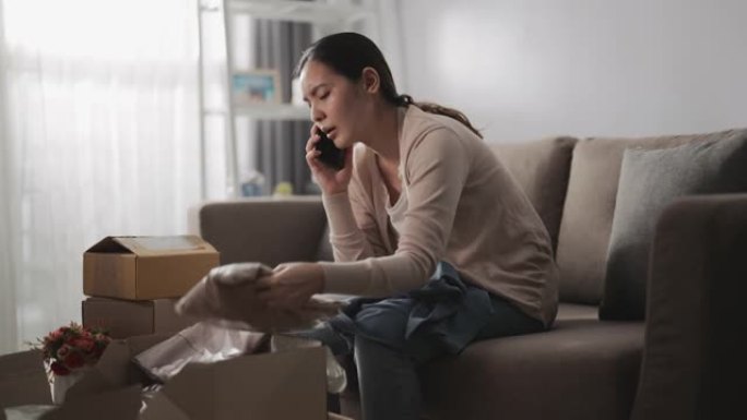 亚洲女性消费者感觉不好坐在沙发上，在网上与商店联系，询问家里有问题的产品订单，电话投诉。