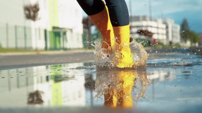 特写: 暴雨后女孩在一个清澈的水坑中奔跑的电影镜头。