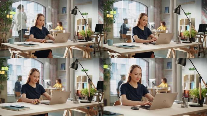 穿着黑色休闲装的美丽女性坐在创意办公室的办公桌前，在笔记本电脑上处理任务。微笑的创意专家为营销议程撰