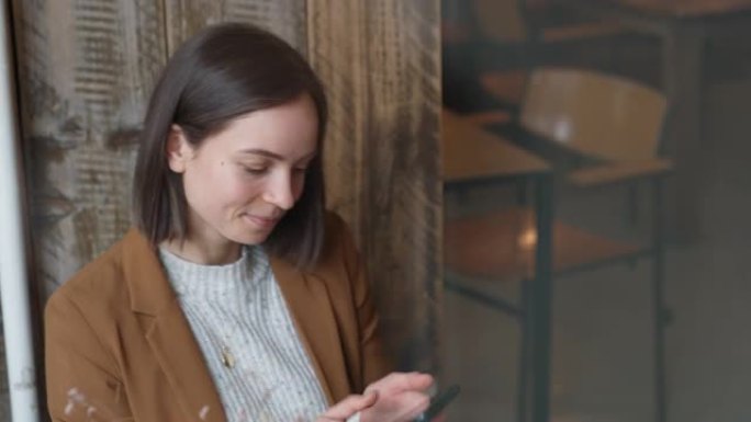 快乐的年轻女子坐在咖啡店里用手机