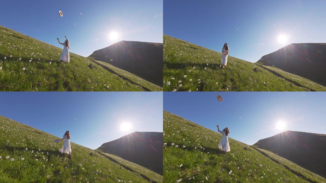 穿着白色长裙的SLO MO女人在满是水仙花的草地上向空中举起帽子