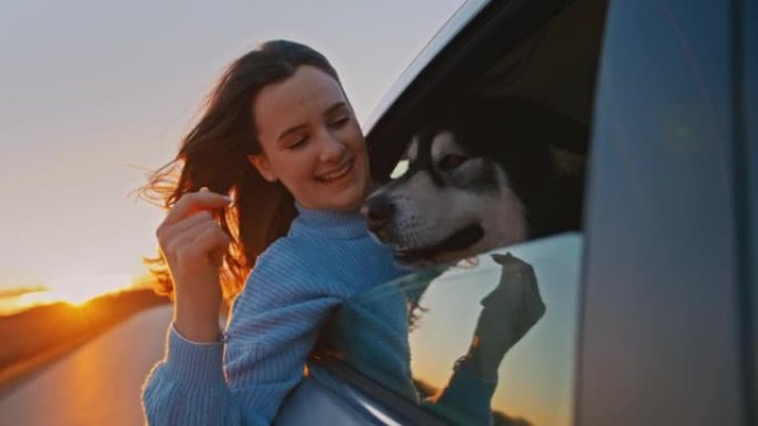 快乐的年轻女子，她的狗坐在汽车后座上，看着窗外
