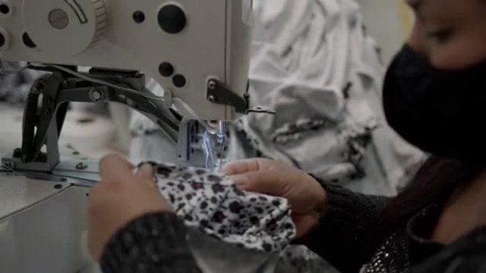 在纺织厂的生产线上缝制衣服的女人