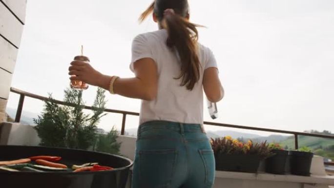 女人在阳台上烧烤蔬菜时跳舞