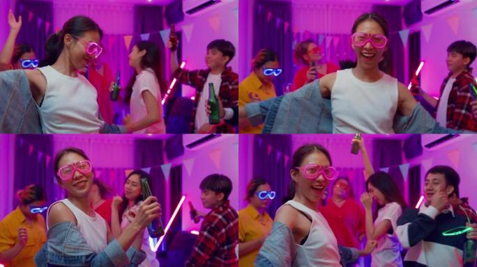 多元群体多民族年轻的亚洲朋友戴着未来派霓虹灯发光眼镜跳舞和喝酒精啤酒有趣的聚会在客厅晚上室内家庭。