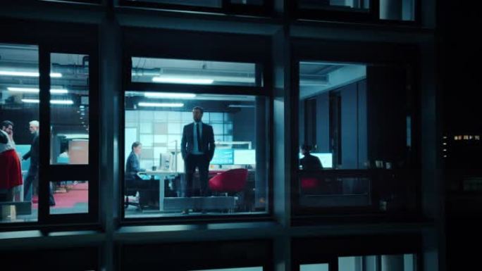 窗外的镜头: 严肃的商人走向办公室的窗户。业务经理和财务专家在后台工作。员工若有所思地看着远方。