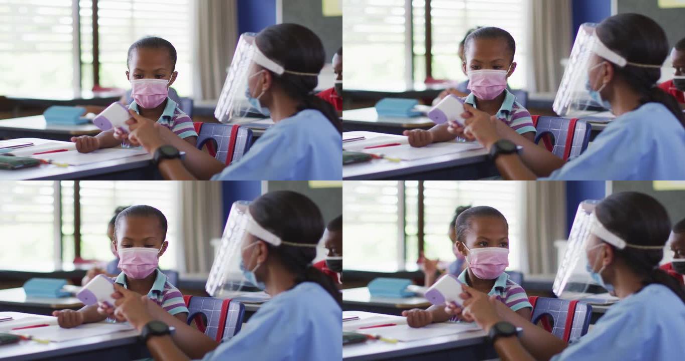多元化的医务人员向女学生展示如何测量温度，都戴着口罩，