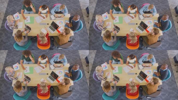 大学或大学生坐在桌子旁与导师坐在一起的头顶镜头